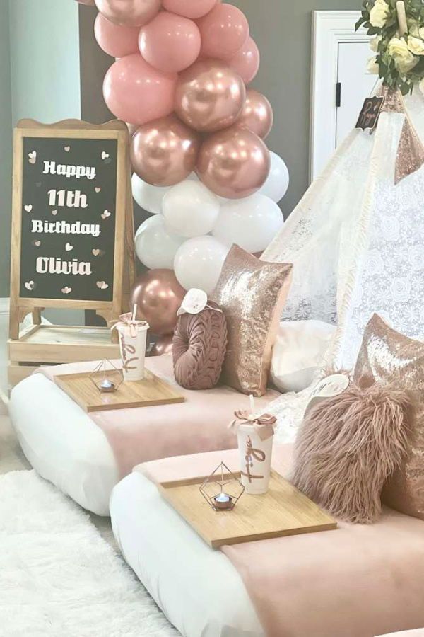 a birthday party with balloons and decorations on the table, including pink couches and pillows