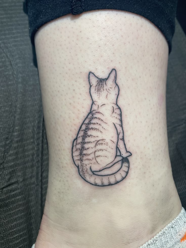 a cat tattoo on the side of a woman's lower back ribcage