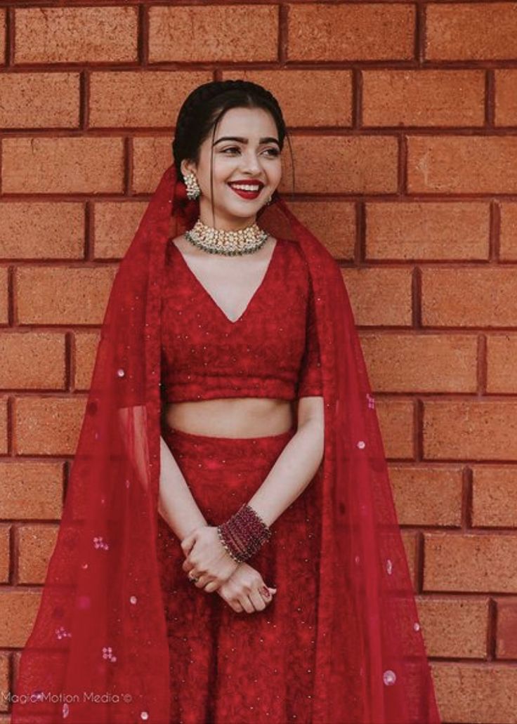 a woman in a red outfit standing next to a brick wall