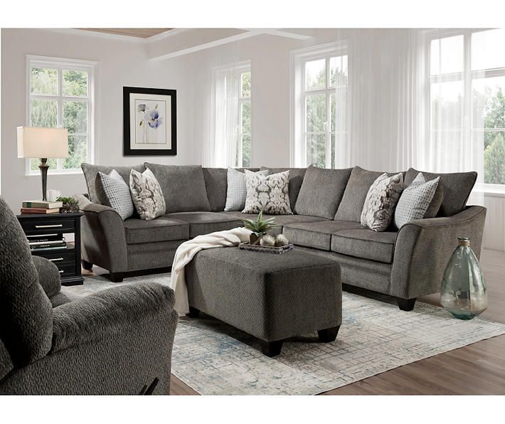 a living room with gray couches and white curtains on the windows sill, coffee table and ottoman