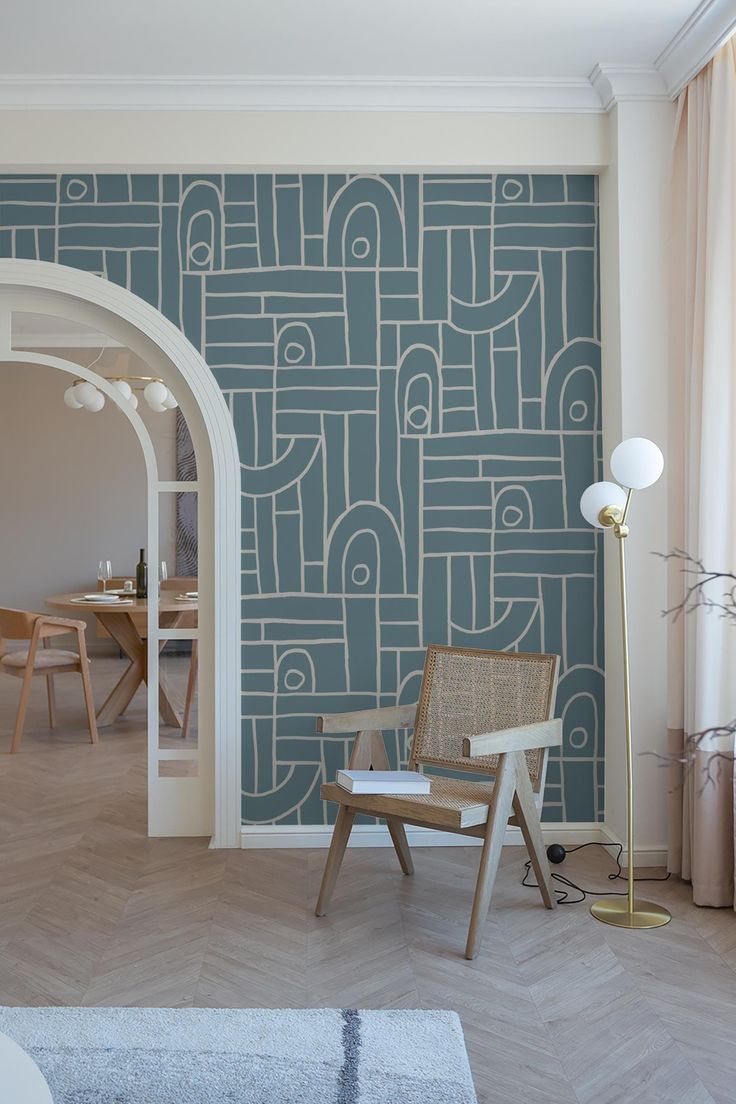 a chair sitting in front of a blue wall with geometric designs on it and a lamp next to it