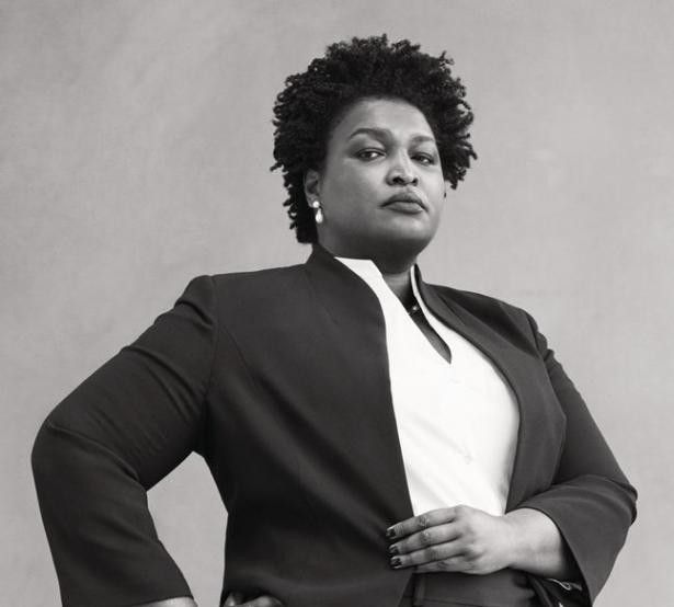 a black and white photo of a woman with her hands on her hips wearing a suit