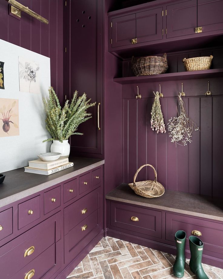 a purple kitchen with wooden cabinets and brass handles