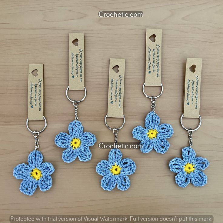 four crocheted key chains with flowers attached to them