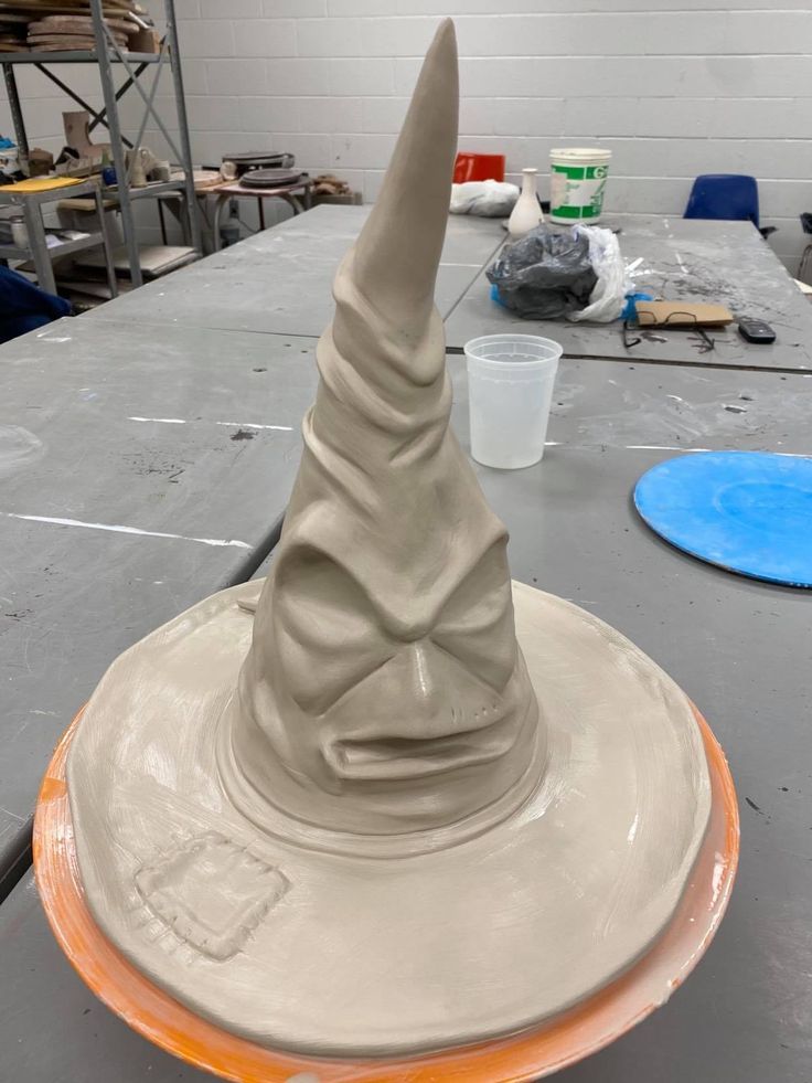 a clay wizard's hat sitting on top of a table in a room filled with other items