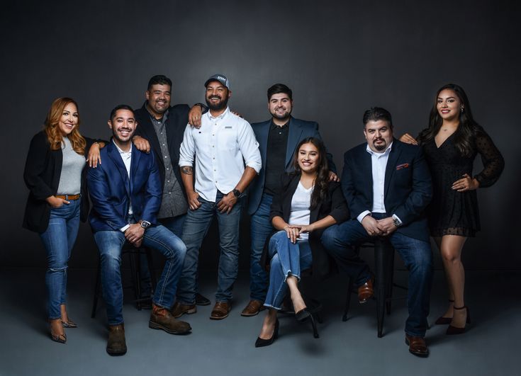 a group of people standing and sitting in front of a black background posing for a photo