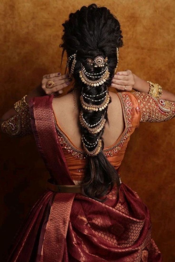 a woman with long black hair in a red dress and gold jewelry on her head