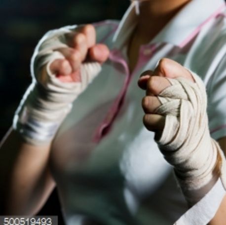 a woman with bandages on her hands is making a fist gesture while standing in front of a dark background