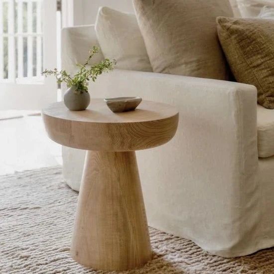 a white couch sitting next to a wooden table on top of a carpeted floor