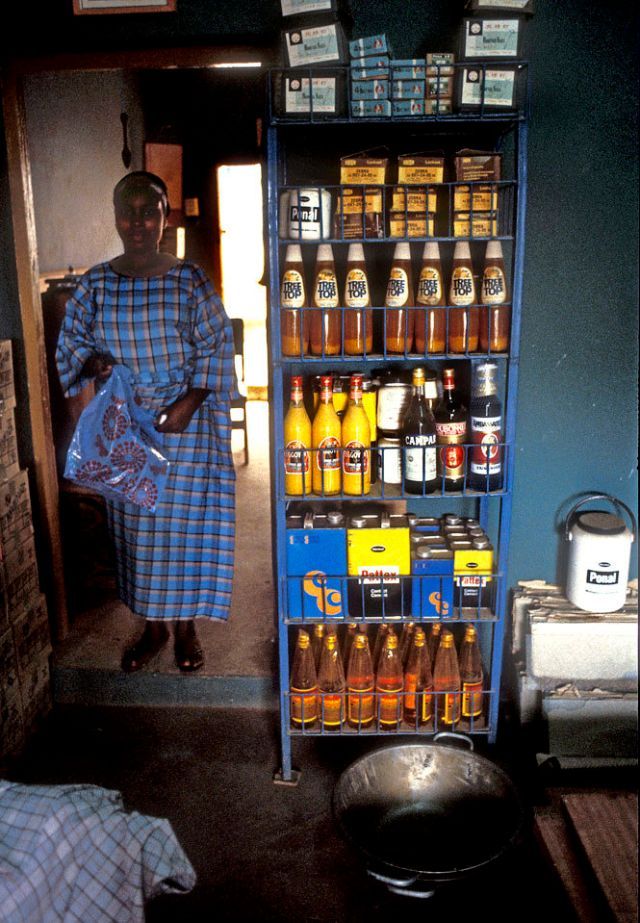 a woman standing next to a shelf filled with bottles