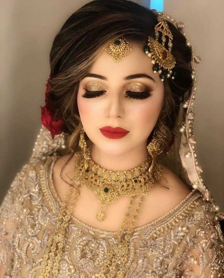 a woman with makeup and jewelry on her face, wearing a bridal outfit that is gold