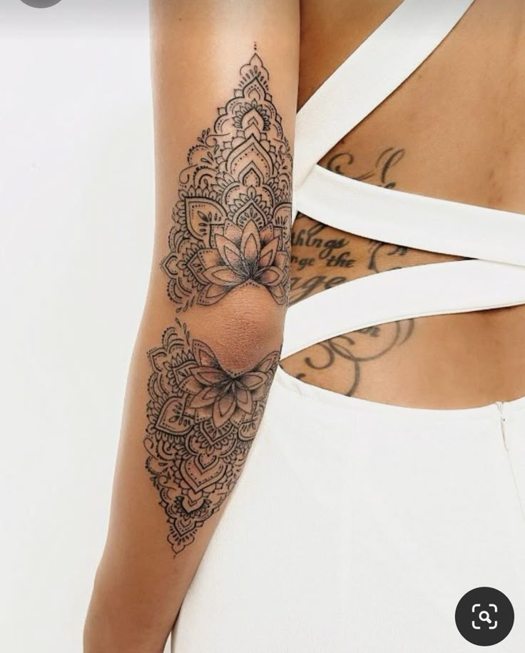 the back of a woman's arm with an intricate tattoo on her left arm