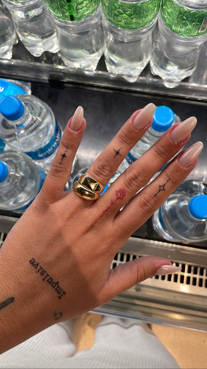 a woman's hand with blue fingernails and tattoos on her left wrist next to water bottles