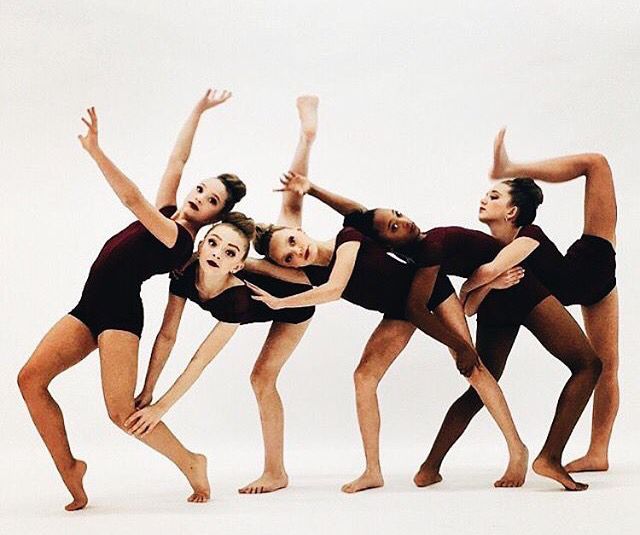 five young women in leotards are posing for a photo with their hands together