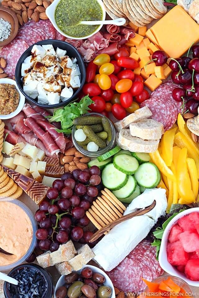 an assortment of cheeses, crackers, fruits and vegetables on a platter