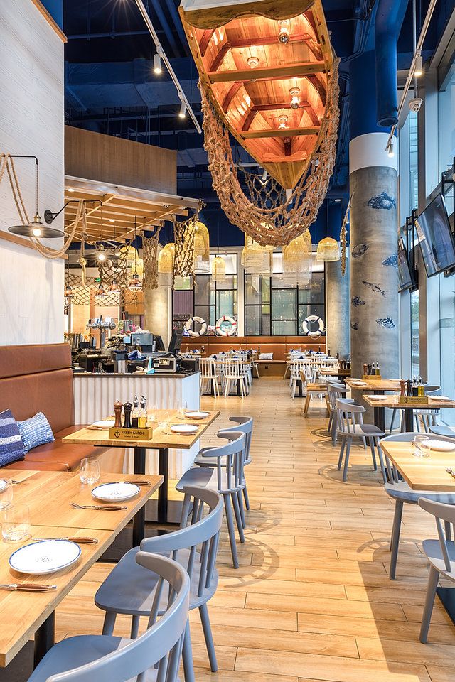 an empty restaurant with wooden tables and blue ceiling lights hanging from the rafters above