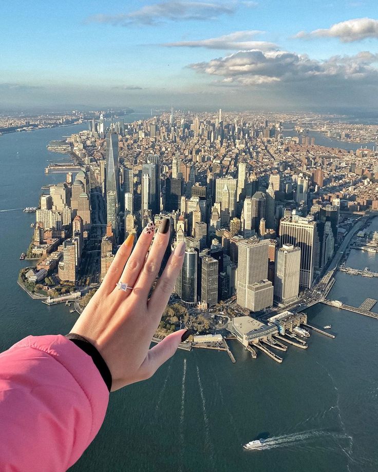 a person's hand reaching out to the view of a city from an airplane