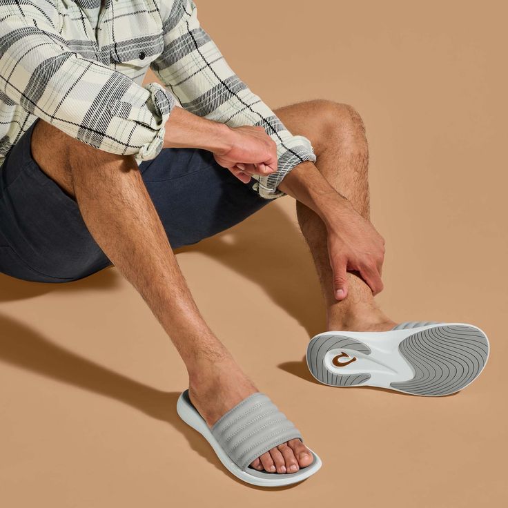 Drawing inspiration from sporty sneakers, the Komo Slide combines the ease of a slip-on with the comfort of OluKai. Featuring a cushioned footbed and a snug, water-resistant strap, this slide is designed for effortless entry and superior comfort. The name 'Komo,' meaning "to enter" or "to go into," aptly reflects the slide's readiness to accompany you in every step of your day, whether you're hitting the beach or the streets. Key Features: Water-Repellent Material: Crafted with water-repellent s Relaxing Backyard, Mens Slide Sandals, Sporty Sneakers, Beach Slides, Promotional Products Marketing, Men's Sandals, Plus And Minus, Beach Sandals, Sleek Look