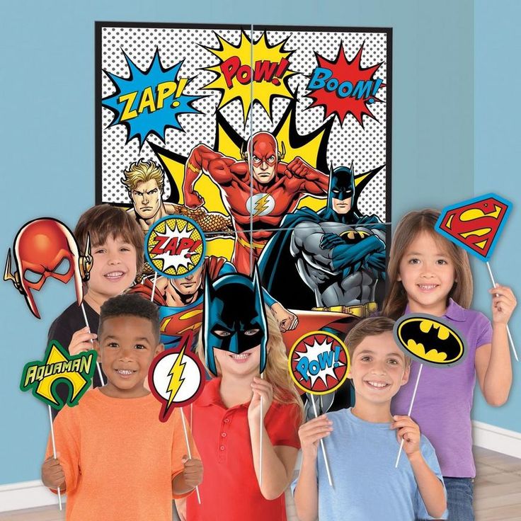 a group of children standing next to each other in front of a wall with superheros on it