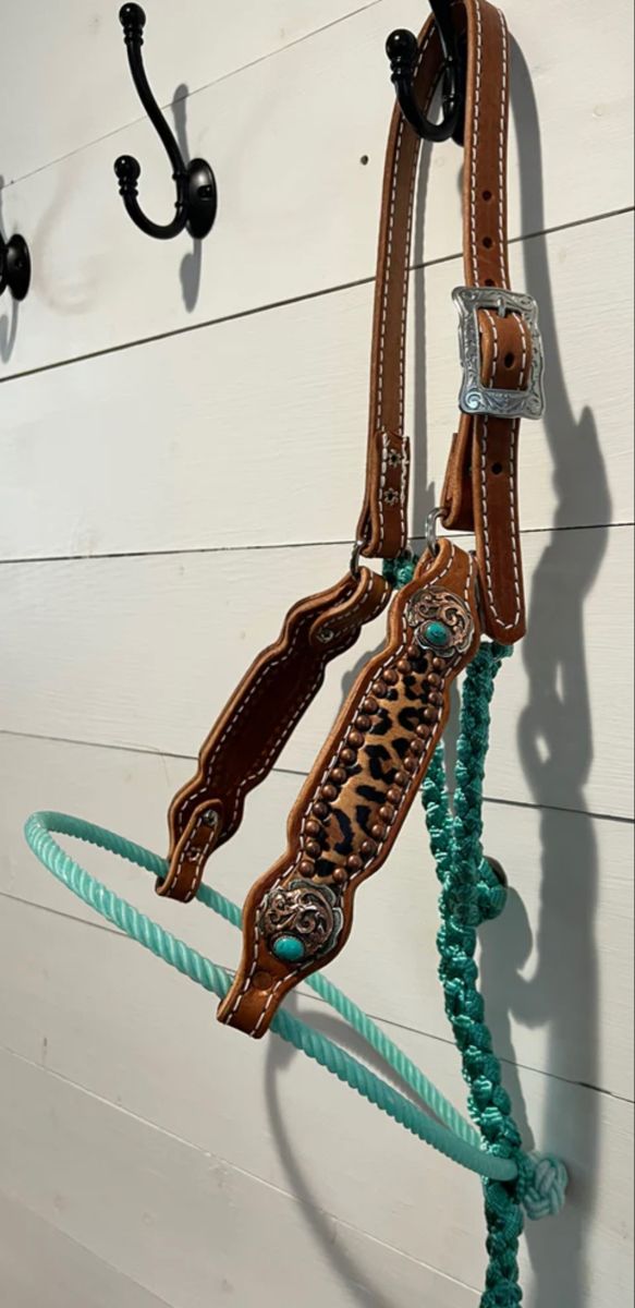 a horse bridle hanging on the side of a white wall with turquoise beads