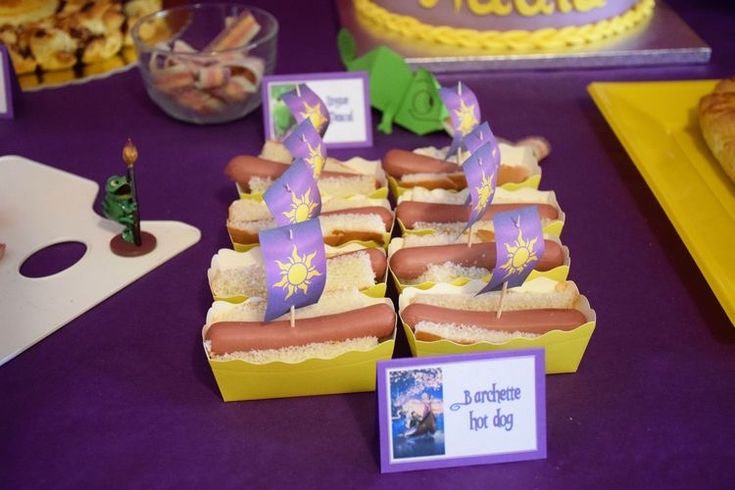 a table topped with lots of hot dogs covered in buns next to other food