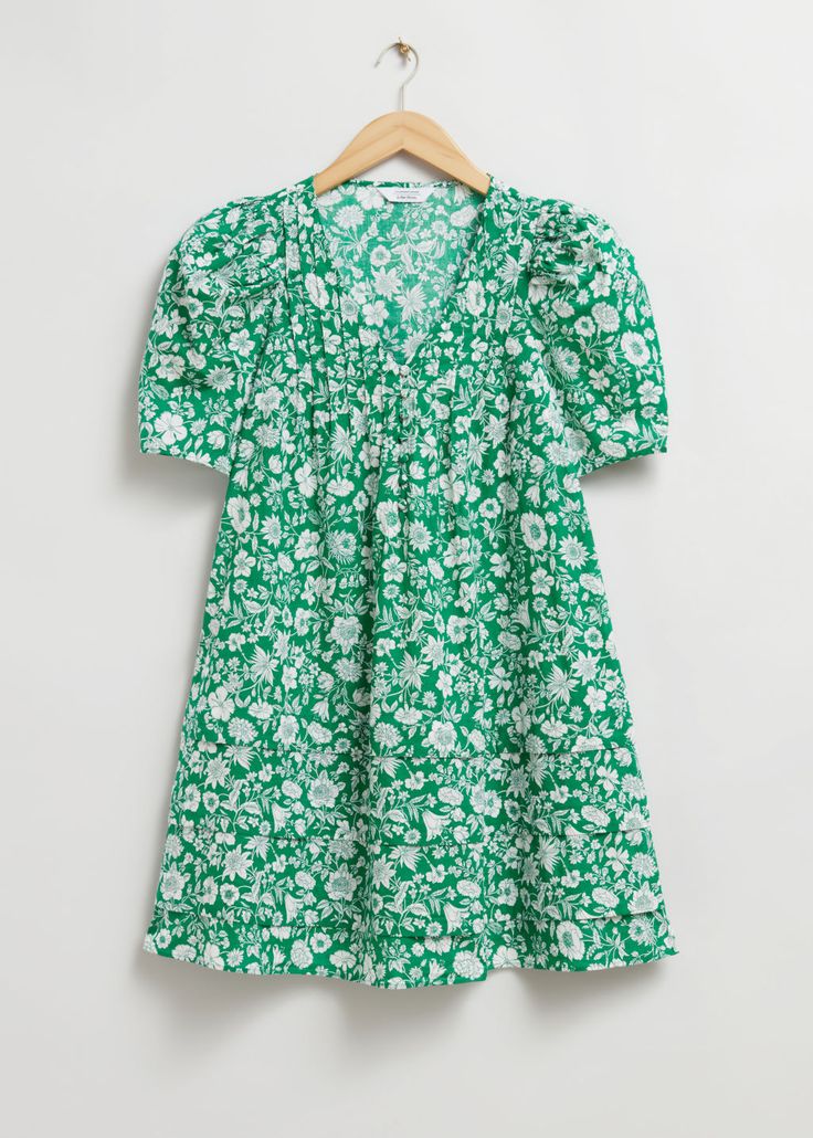 A-line short-sleeve dress designed with a v-cut neckline decorated with pintuck pleats, a half-buttoned front, and rounded puff sleeves. The skirt is cut in a loose-fit silhouette with tiered stitch detailing.Length of dress: 86cm / 33.9" (EU 36 / UK 8 / US 4) Green V-neck Puff Sleeve Dress With Gathered Sleeves, Green Puff Sleeve Dress With Floral Print, Spring V-neck Dress With Gathered Neckline, Green Puff Sleeve Dress With Gathered Sleeves, Summer Pleated V-neck Dress With Short Sleeves, Short Sleeve Dress With Gathered Neckline For Spring, Casual Green Puff Sleeve Dress, Green V-neck Short Sleeve Spring Dress, Ruched Short Sleeve Mini Dress For Daywear