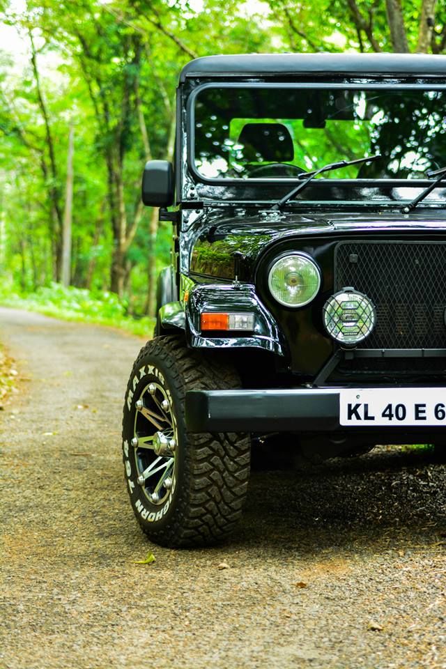 a black jeep parked on the side of a dirt road in front of some trees