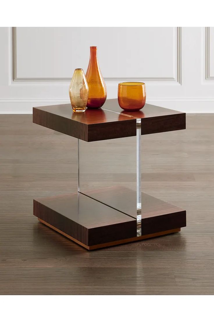 two vases sitting on top of a wooden table in front of a white wall