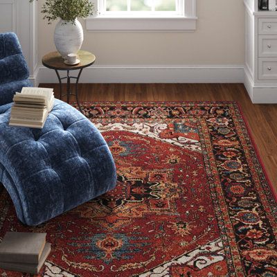 a blue chair sitting on top of a wooden floor next to a rug and window