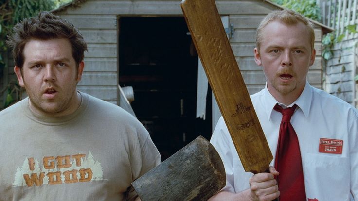 two men standing next to each other in front of a shed holding an axue