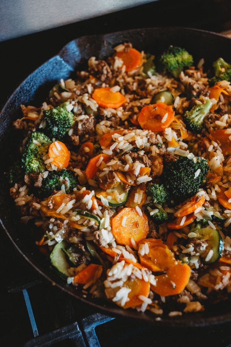 a skillet filled with rice, carrots and broccoli