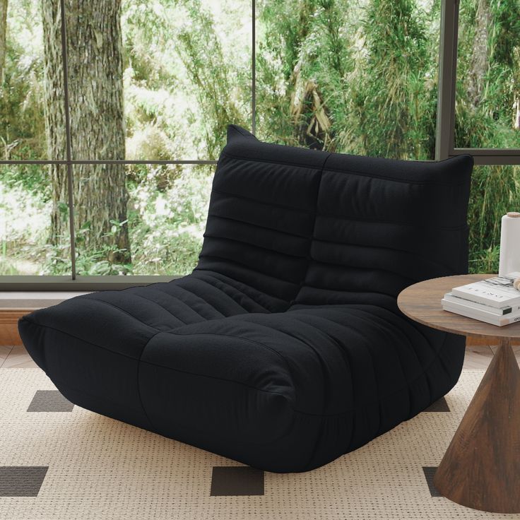 a black bean bag chair sitting on top of a rug next to a coffee table