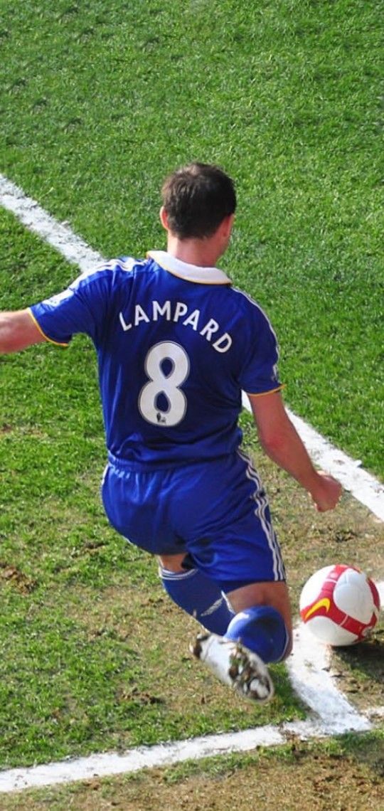 a man kicking a soccer ball on top of a field