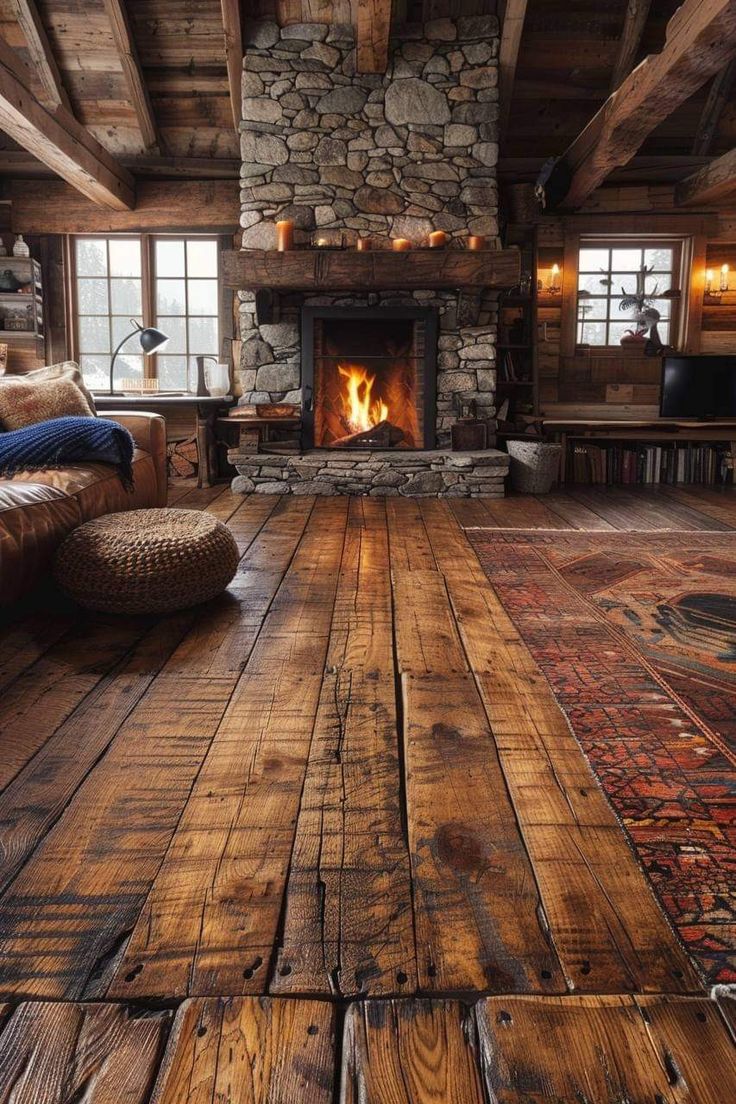 a rustic living room with wood floors and stone fireplace