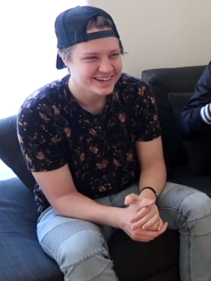 two young men sitting on a couch laughing