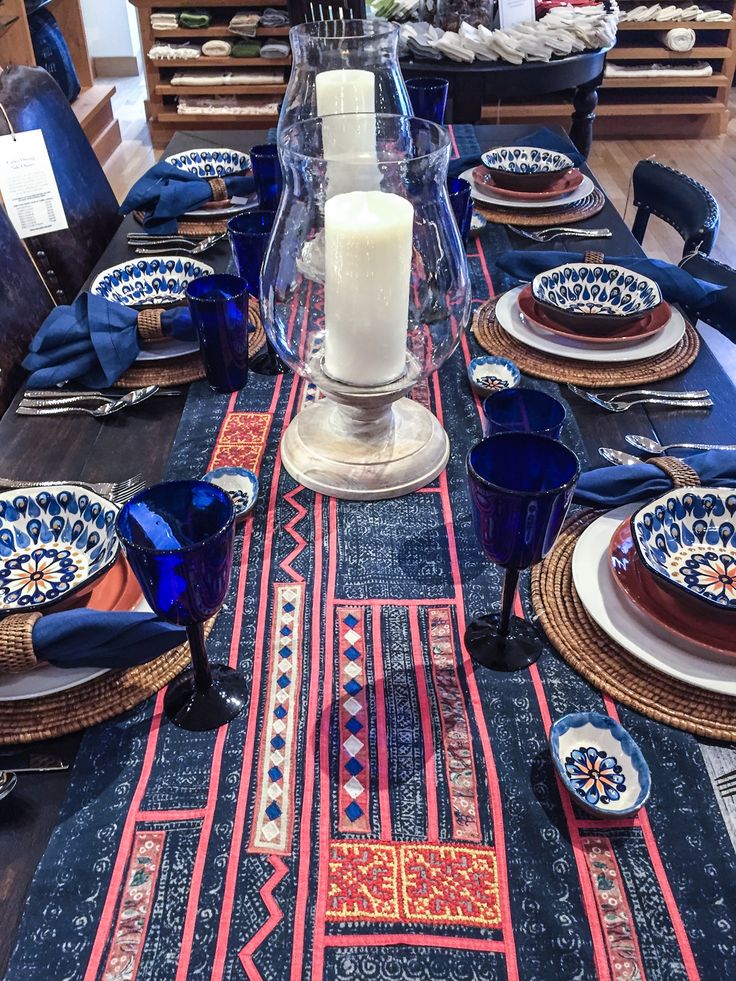 the table is set with blue and red plates, placemats, and candles