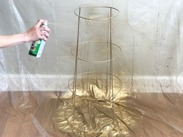 a person holding a spray bottle next to a metal rack with gold foil on it