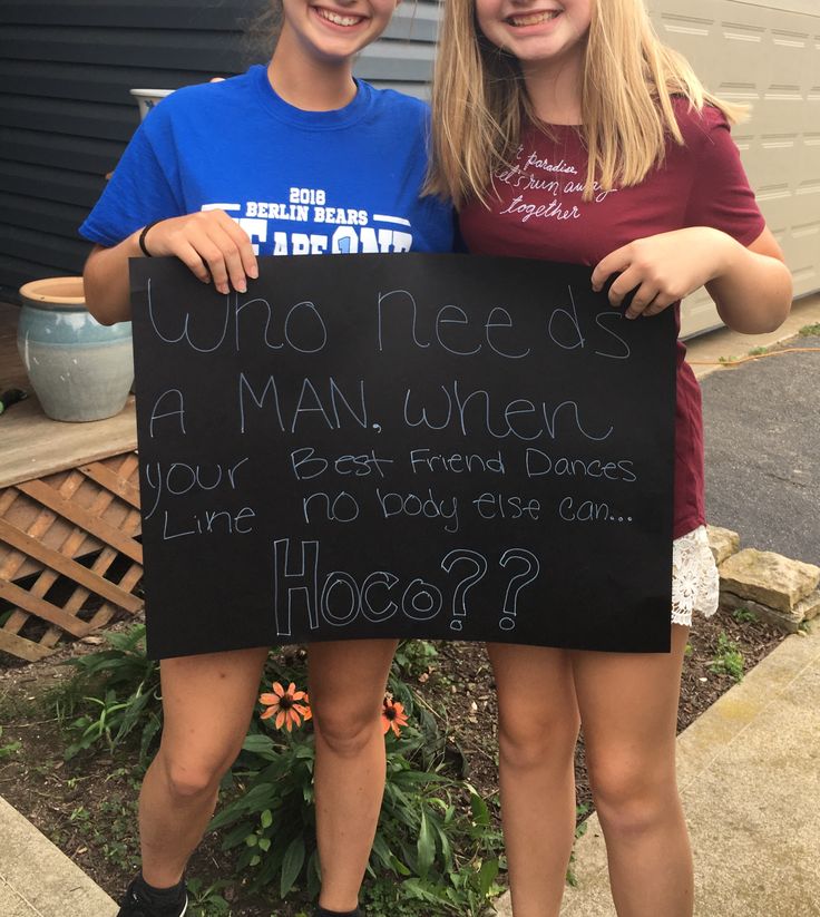 two girls standing next to each other holding a sign