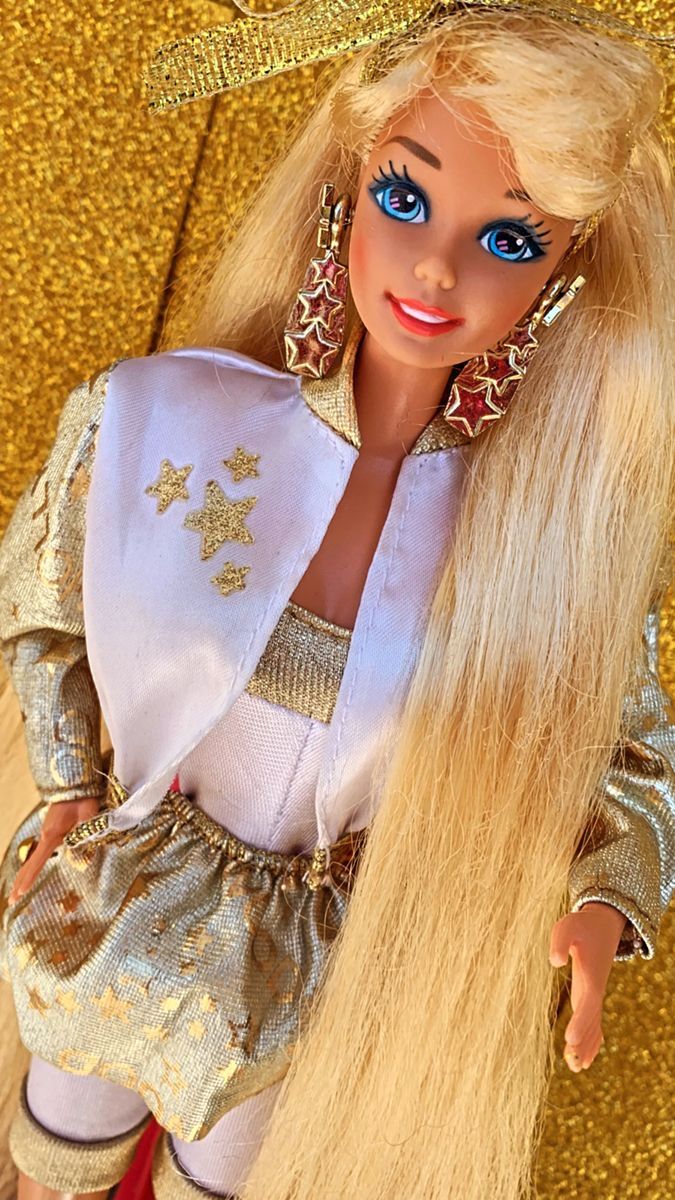 a barbie doll with long blonde hair and blue eyes wearing a white dress, gold sequins