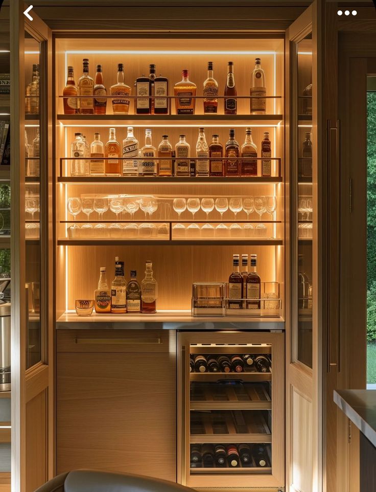 an open refrigerator filled with lots of bottles and glasses on it's shelves next to a window