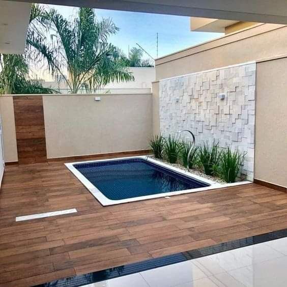 an empty swimming pool in the middle of a patio with wood flooring and tile walls