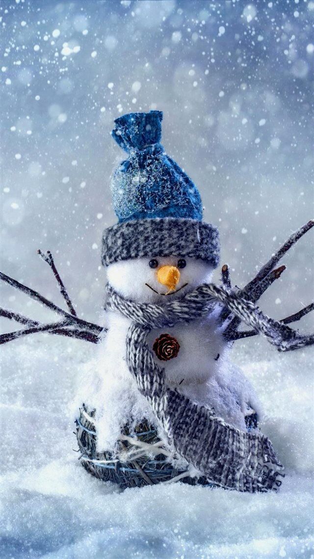 a snowman is sitting in the snow wearing a knitted hat and holding skis