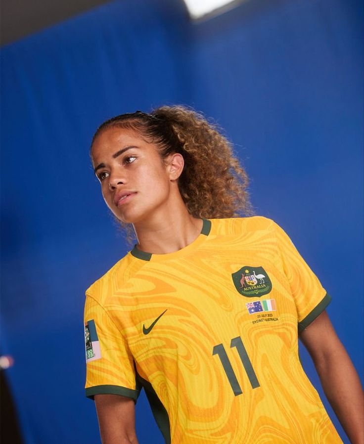 a woman in a yellow soccer jersey is posing for the camera with her hands on her hips