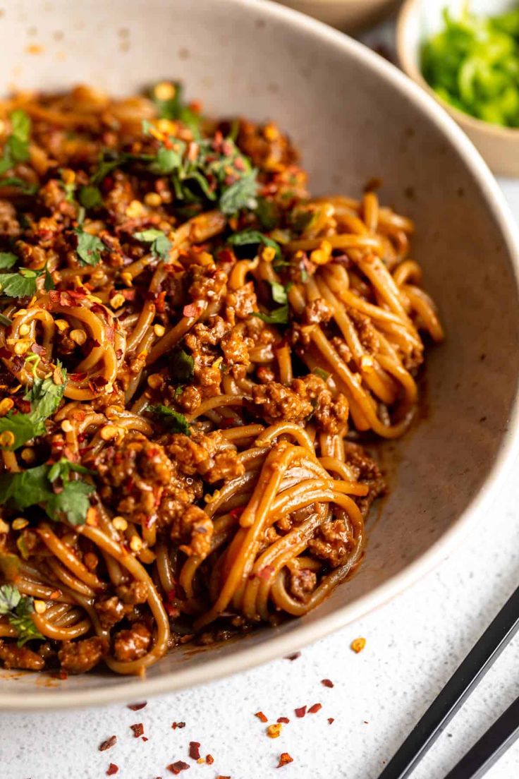 a white bowl filled with noodles and meat