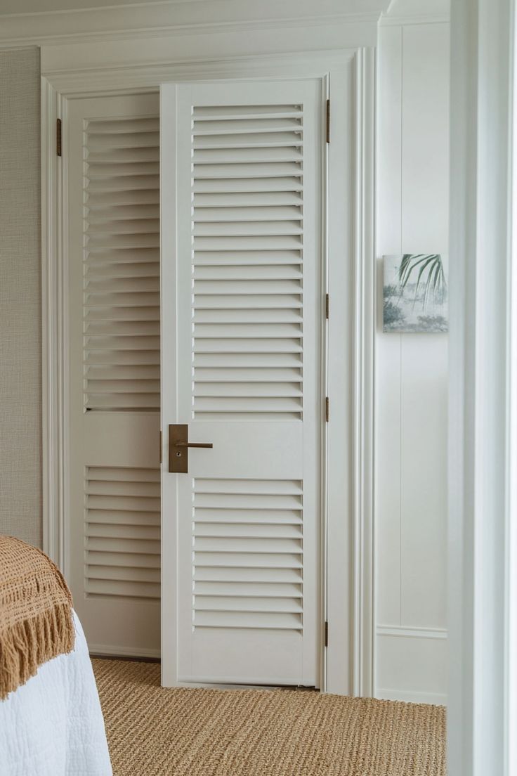 a bedroom with a bed and white shutters on the door way to another room