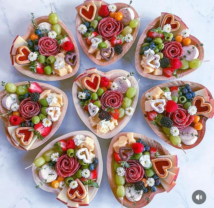 several heart shaped trays filled with fruit and veggies arranged in the shape of hearts