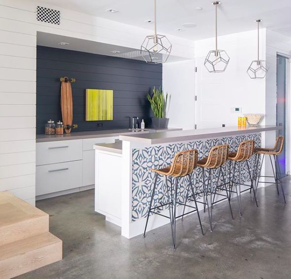 a modern kitchen with bar stools next to the counter and stairs leading up to it