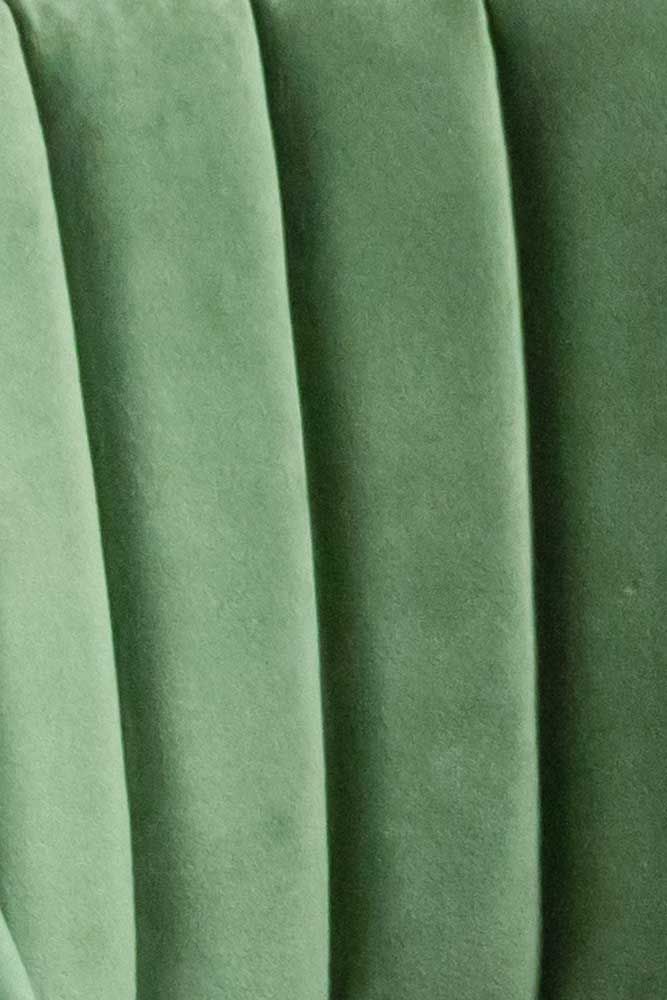 close up view of green velvet fabric with vertical pleating on the top and bottom