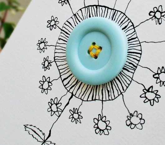 a blue button sitting on top of a piece of paper with flowers in the background