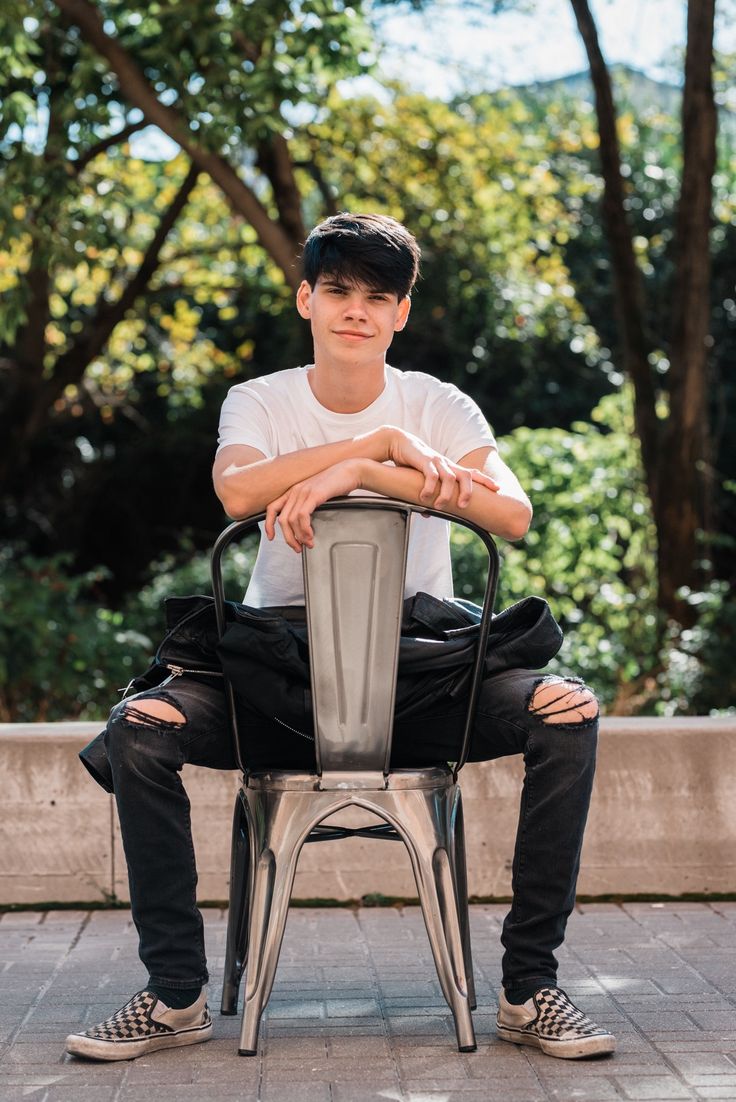 a young man sitting on top of a metal chair